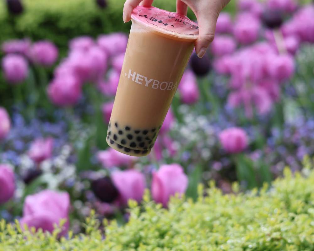 HEYBOBA milk tea with tapioca pearls among colourful flowers